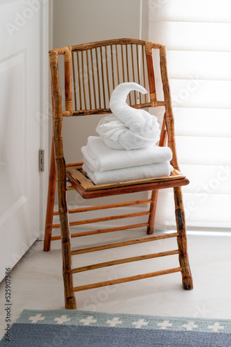 Fototapeta Naklejka Na Ścianę i Meble -  White guest bath towel folded in fancy style in shape of swan sitting atop stack of towels on chair in bed and breakfast hotel bathroom