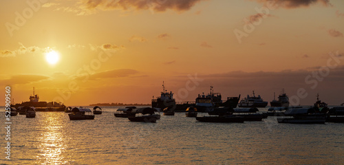 ZANZIBAR, TANZANIA - SEPTEMBER 2019: Lots of boats in the water at the sunset in the background of orange sky © Анастасия Смирнова