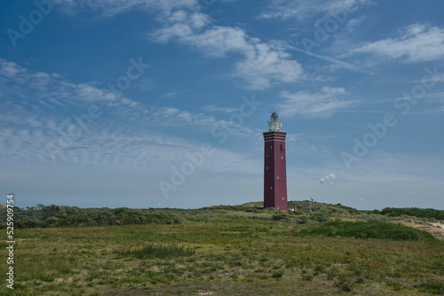 Square and solid Westhoofd lighthouse South Holland with beach  sand dunes  blue skies  dune flowers and puffy clouds.