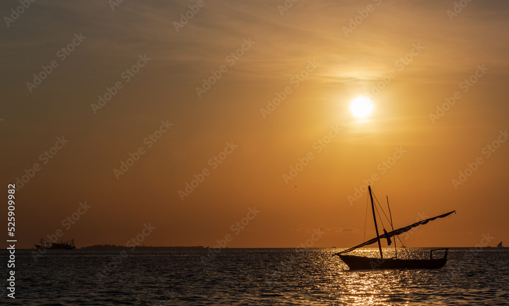 ZANZIBAR, TANZANIA - SEPTEMBER 2019: Boat with sailing at the sunset in the background of yellow sky