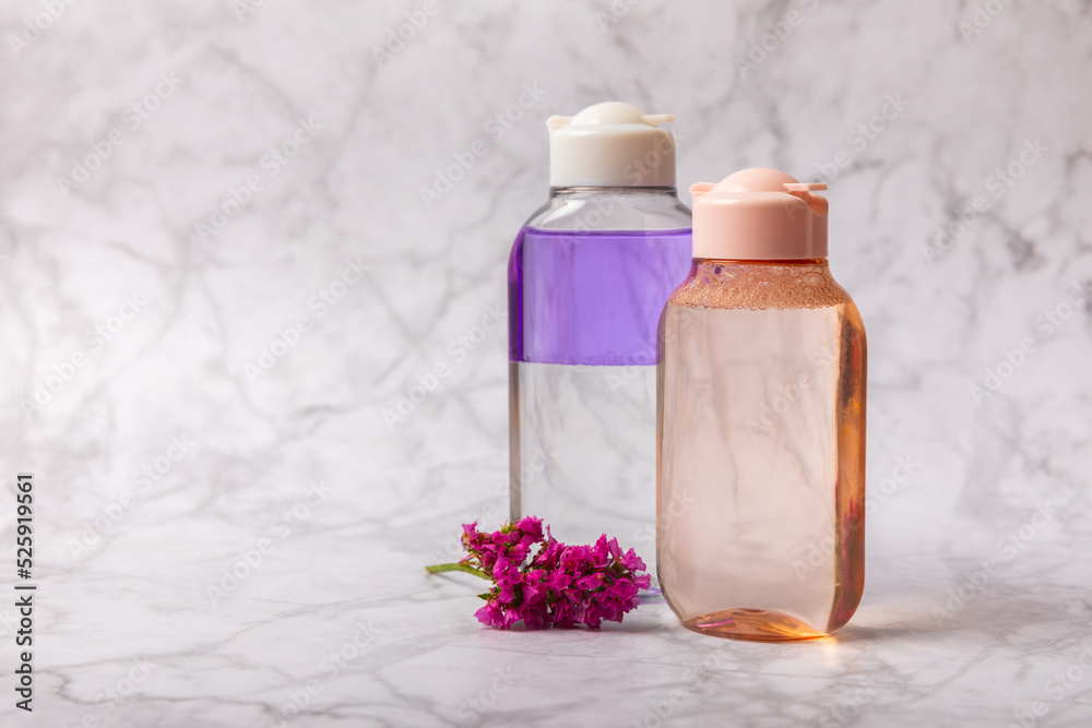 Face care for the face, tonic or lotion, micellar water with pink flowers on a marble background.Beauty concept.Freshness and naturalness Anti-aging care. Women's daily fresh cosmetics. Copy space. Face care for the face, tonic or lotion, micellar water with pink flowers on a marble background.Beauty concept.Freshness and naturalness Anti-aging care. Women's daily fresh cosmetics. Copy space.
