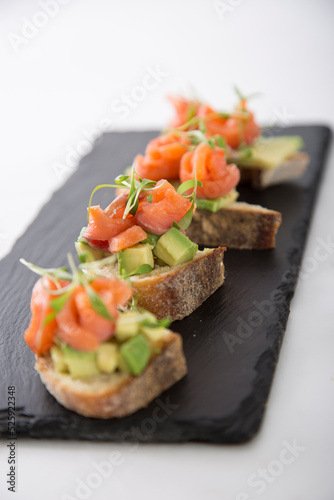 Salmon trout bruschetta on bread pieces with avocado and micro greens snack food