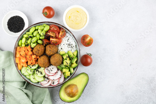 Poke bowl: rice, falafel, avocado,tomatoes,beans, cucumbers. Buddha bowl: rice, falafel, vegetables on gray background.
