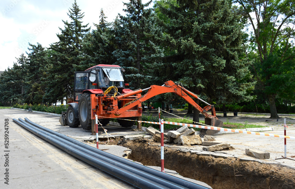 Laying of urban communications. plastic pipes lie next to the trench. replacement of rusty metal pipes with new plastic ones. A trench dug by a tractor Laying of urban communications. plastic pipes lie next to the trench. replacement of rusty metal pipes with new plastic ones. A trench dug by a tractor