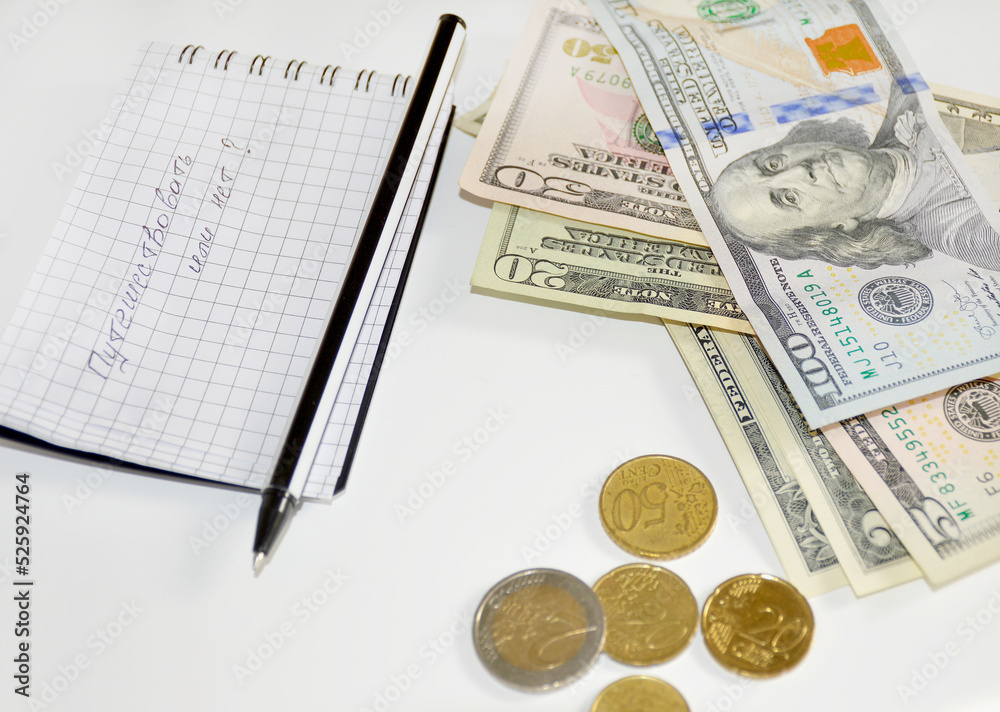 Obraz premium Notebook entry in Russian: to travel or not. counting money for summer holidays and a trip to the sea. notebook, pen, dollars and coins on a white background