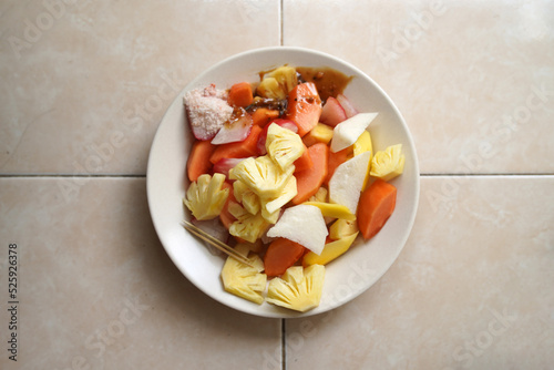 Rujak buah or indonesian fruit salad on white plate, served with spicy brown sugar sauce and ground peanuts. photo