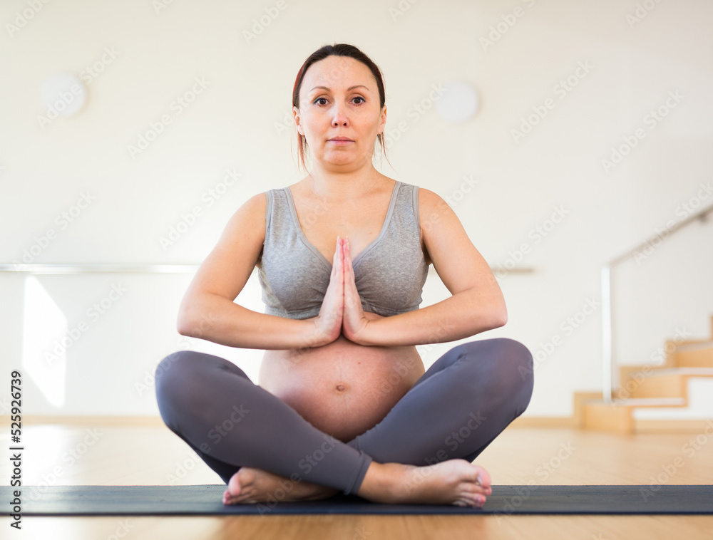 pregnant woman is engaged in yoga. Easy pose or Sukhasana.