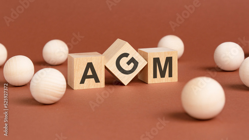 wooden cubes with word AGM on brown background. front view photo