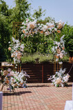A beautiful arch decorated with flowers and lamps stands in the park at the wedding ceremony.