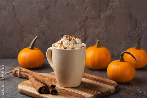 Autumn pumpkin spice latte with cream in mug on dark table. Traditional Coffee Drink for Autumn Holidays. Harvest Festival, Happy Thanksgiving. Fall time. Home comfort.