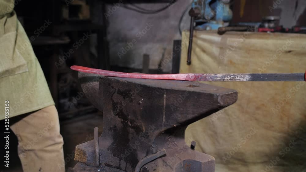 Close-up of a blacksmith hitting a red-hot metal billet on an anvil in the forge with a hammer. Close-up of a blacksmith hitting a red-hot metal billet on an anvil in the forge with a hammer.