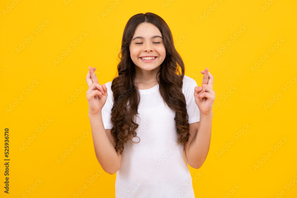 Teenager child girl crossing her fingers and wishing for good luck, isolated on yellow studio background with copy space. Teenager child girl crossing her fingers and wishing for good luck, isolated on yellow studio background with copy space.