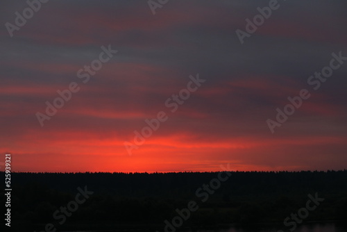 Colorful landscape of the sunset red sky over the black silhouette of the forest