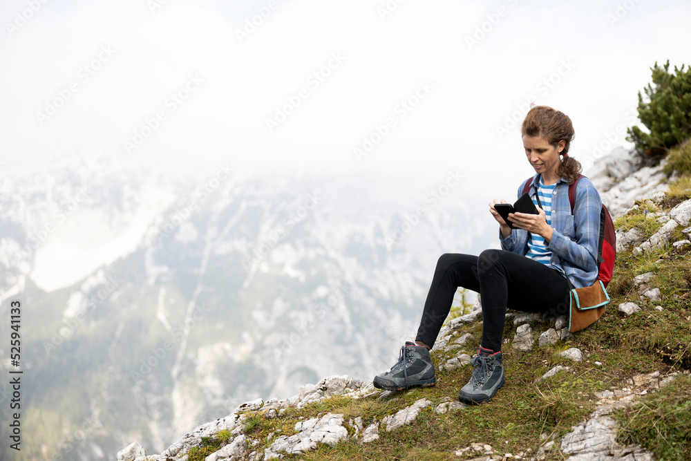 Naklejka premium Woman Hiker with sitting on floor outdoors texting on a Cellular