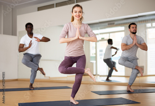 Young woman doing yoga postures on mat during group yoga training.