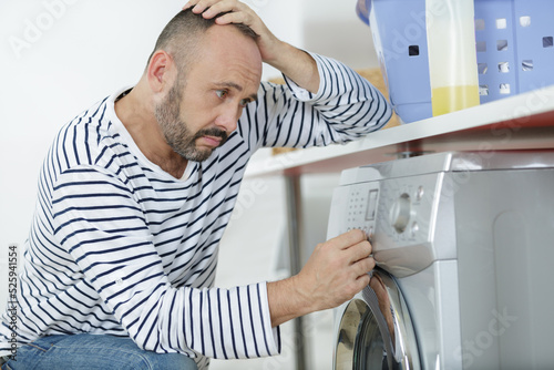 upset man sitting next to washing machine