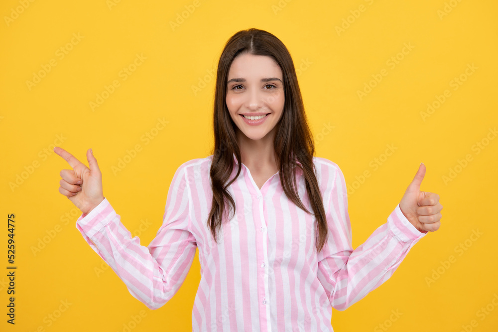 Woman point at copy space, showing copyspace pointing. Promo, girl showing advertisement content gesture, pointing with hand recommend product. Isolated yellow background.
