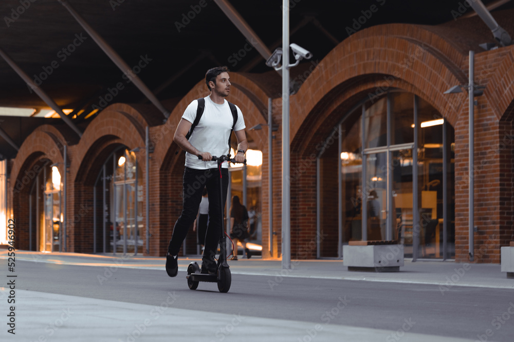 Handsome Young Man Having Fun Driving Electric Scooter Outdoors In Modern Park.