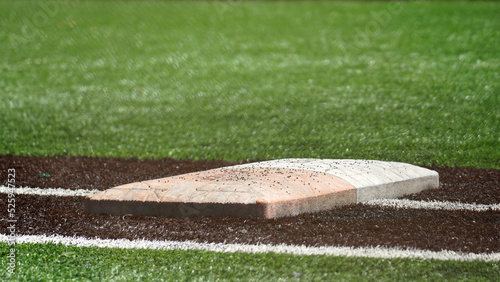 Ground level view of first base and safety bag on a turf baseball and softball field.