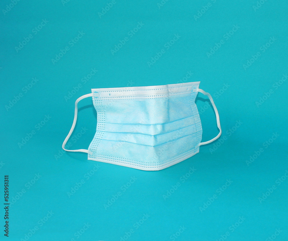 Medical mask with rubber earmuffs isolated on a blue background. Three-layer protection. Corona protection, pollution, virus, flu and medical care and surgical concept. Medical mask with rubber earmuffs isolated on a blue background. Three-layer protection. Corona protection, pollution, virus, flu and medical care and surgical concept.