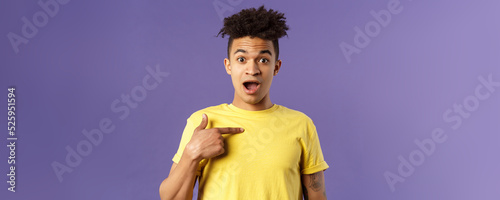 Who me, no way. Portrait of surprised, happy rejoicing young man looking with disbelies as being chosen from all candidates, pointing at himself open mouth fascinated, purple background