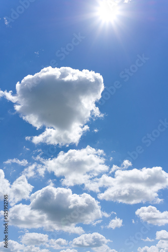 A few white clouds in a blue sky and a bright sun. Wide angle. Vertical snapshot