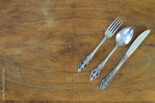 Overhead shot of silverware on wooden table with copy space.