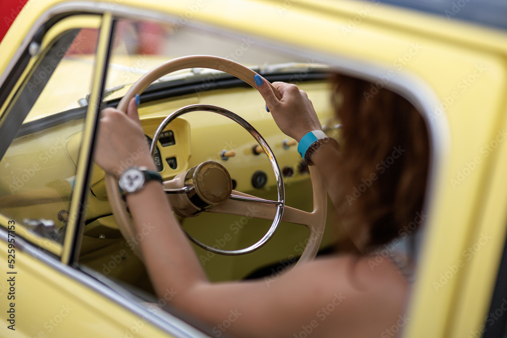 Beautiful brunette girl in sunglasses driving a bright yellow retro car