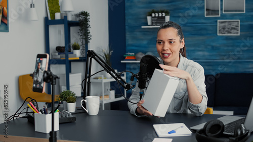 Popular tech enthusiast doing unboxing review video in living room studio. Famous social media influencer doing product recommendation video while presenting specifications to audience.