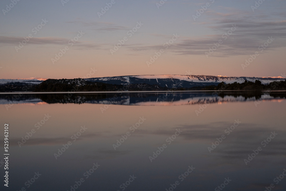 Magical alps. Panorama view of the tranquil lake and mountains in the horizon at sunset. Beautiful dusk colors in the environment, landscape and sky reflection in the water surface.