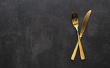 Gold knives and forks set against a black background. Beautiful gold cutlery.