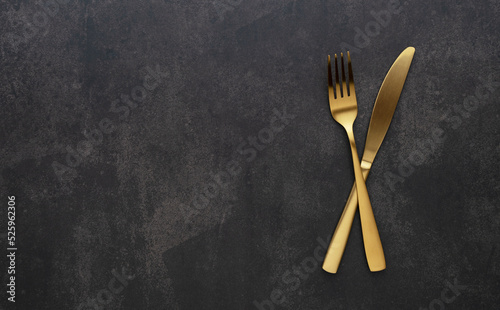 Gold knives and forks set against a black background. Beautiful gold cutlery.