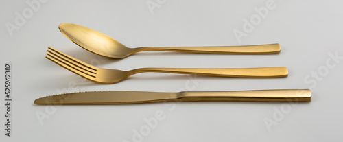 Gold knives, forks and spoons placed on a white background. Beautiful gold cutlery.