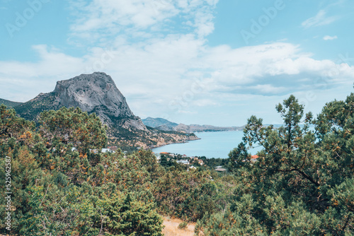 A nature scenery of a calm sea and green bushes, with Lions Head mountain in the horizon. Landscape of the ocean near the mountains with blue cloud sky and copy space. High quality photo