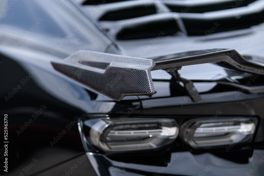 Luxury black sports car fragment, rear aerodynamics carbon spoiler