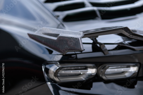 Luxury black sports car fragment, rear aerodynamics carbon spoiler and rear lights photo