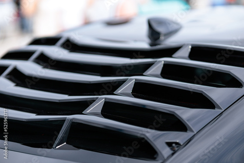 Sport car at the start. Grille on the rear window of the car. Luxury black sports car fragment, rear aerodynamics carbon spoiler and rear lights.