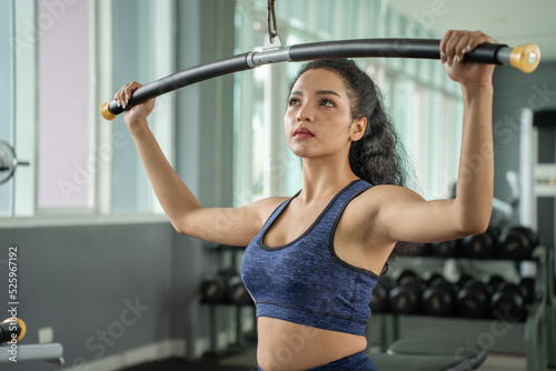 beautiful muscular fit woman exercising building muscles. Muscular athletic female bodybuilder pulled on sports simulator.