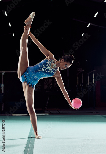 Fitness, sports and training for a woman gymnast with ball, in professional arena. Exercise, motivation and energy for a girl in a gymnastics competition. Performance with rhythm, beauty and balance.