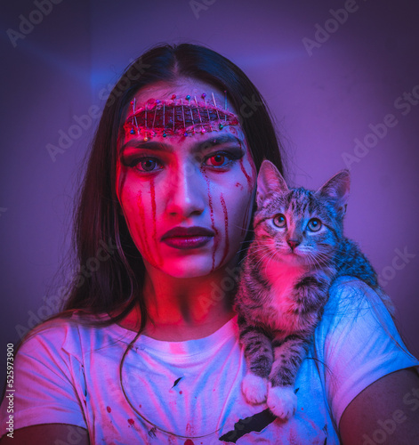 Fototapeta Naklejka Na Ścianę i Meble -  Portrait of a teenage girl with horror halloween makeup and different colored eyes with a cat on her shoulder