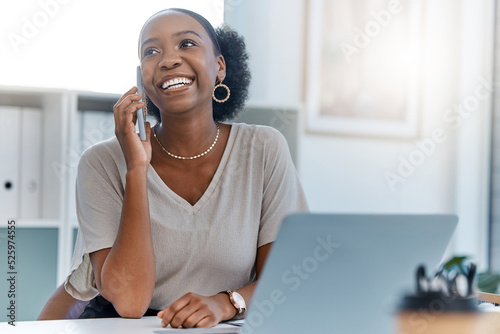 Happy business woman smile talking on phone call or young entrepreneur answering cellphone while sitting in front of work laptop in an office. Female executive smiling and laughing at a funny joke