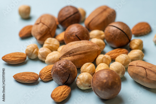 Various nuts scattered on a light background. Almonds, hazelnuts, pecans, macadamia in a pile close up. The concept of healthy eating and snacking