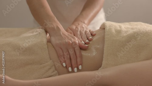 Hands masseur massaging the client. Oil glares on the skin, hands move smoothly over the body.