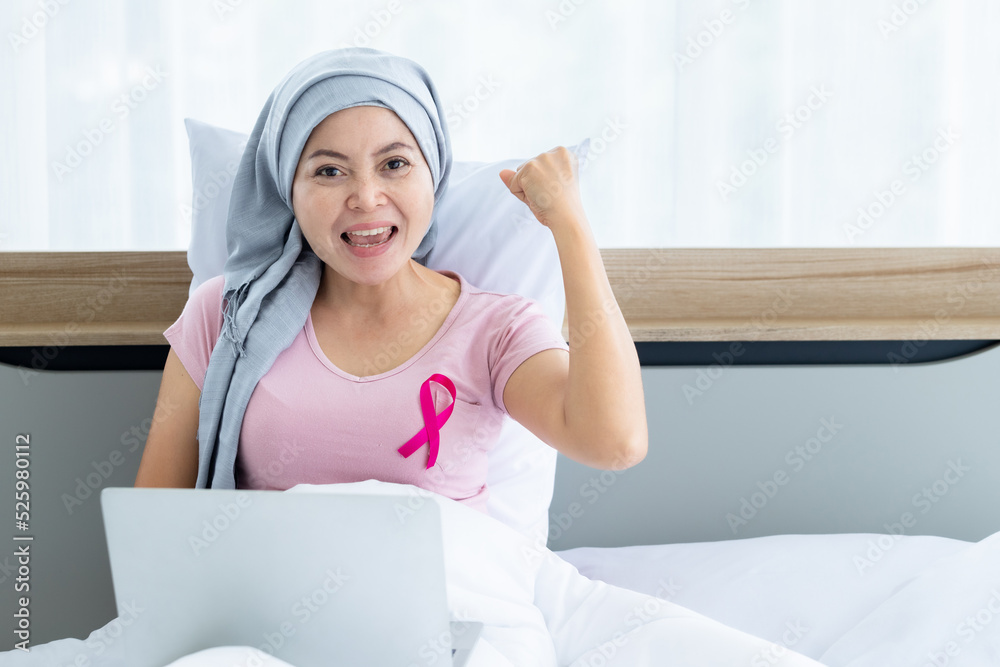 a asian women disease mammary cancer patient with pink ribbon wearing headscarf After treatment to chemotherapy with working business at laptop on bed In the bedroom at the house,healthcare,medicine a asian women disease mammary cancer patient with pink ribbon wearing headscarf After treatment to chemotherapy with working business at laptop on bed In the bedroom at the house,healthcare,medicine