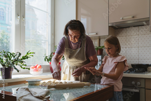 Great-grandmother and granddaughter cook pies in the kitchen.