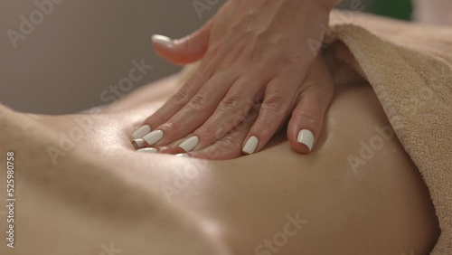 Hands masseur massaging the client. Oil glares on the skin, hands move smoothly over the body.