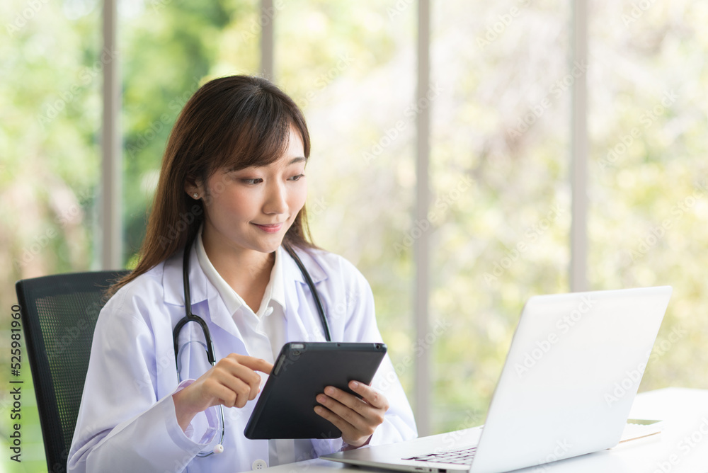 Asian doctor woman sitting and working with her laptop in modern office clinic room. Asian doctor woman sitting and working with her laptop in modern office clinic room.
