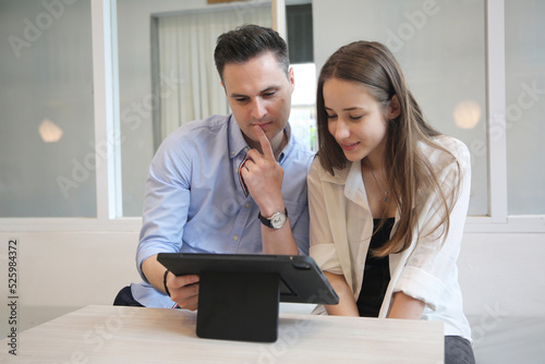 Young attractive woman and young man are interacting with the mobile tablet in cafe.
