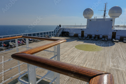 View from open outdoor deck of legendary luxury ocean liner cruise ship on passage during Transatlantic Crossing from Southampton to New York with deck chairs, railing and superstructure photo