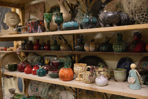 Fototapeta Naklejka Na Ścianę i Meble -  Shelves with finished handmade ceramic dishes in various shapes and colors. Finished pottery hand-sculpted from clay and painted in various colors in the form of mugs, pots and figurines.